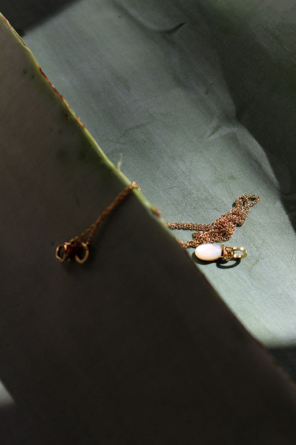 Chaîne en maille fine, dans un style forçat avec un pendentif de forme ovale, monté sur un anneau et un cabochon en nacre.