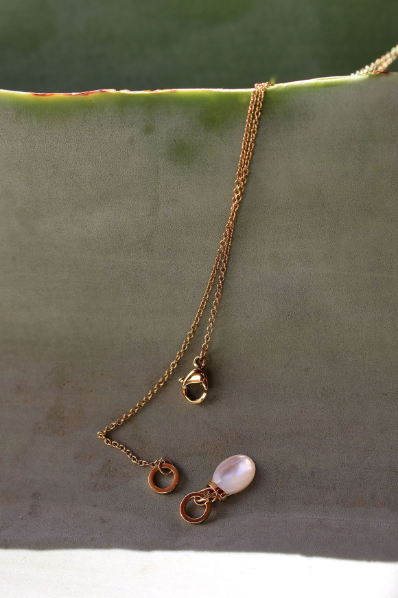 Chaîne en maille fine, dans un style forçat avec un pendentif de forme ovale, monté sur un anneau et un cabochon en nacre.