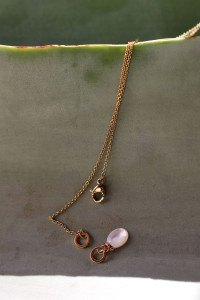 Chaîne en maille fine, dans un style forçat avec un pendentif de forme ovale, monté sur un anneau et un cabochon en nacre.